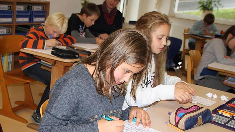 Hausaufgabenbetreuung am Nachmittag: Franziska (von links) und Justine beschäftigen sich still, während im Hintergrund Lehrerin Petra Fabinger Robin und Nikita beim Schreiben hilft. Foto: Ulrike Müller