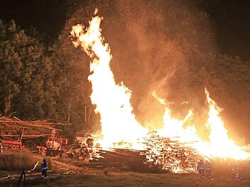 Zahlreiche Feuerwehrleute wurden am späten Montagabend zum Brand eines Holzlagers gerufen. Nachdem das Feuer gelöscht war, riss ein Bagger den Holzhaufen auf, um weitere Glutnester sichtbar zu machen. Fotos: News5/Ferdinand Merzbach