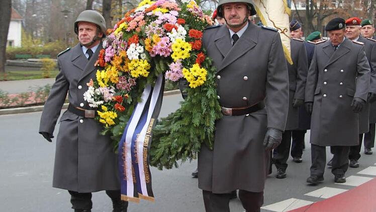 Die Mahnwache, gekleidet in Uniform, trägt den Kranz der Stadt und des Landkreises durch die Stadt und legt ihn in feierlicher Zeremonie am Kriegerdenkmal nieder