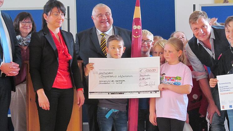 Regierungsschuldirektor Alexander Wunsch (M.) überreicht das Preisgeld von 500 Euro an die Schüler der GS Weißenbrunn mit Rektor Ralf Knöchel (r). Foto; Karl-Heinz Hofmann