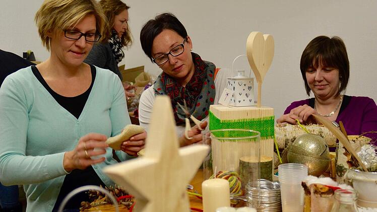 Schnell noch einen Klecks Heißkleber aufbringen und der Zweig hält. Ramona Schlereth (rechts) und Caroline Schlereth sind hier dabei, einen Kerzenständer zu verzieren. Foto: Kathrin Kupka-Hahn