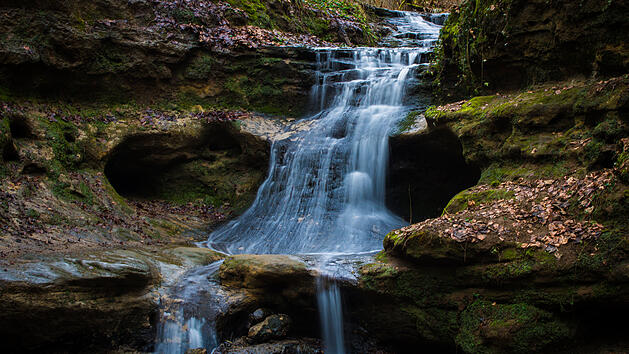 Am Ende der Schlucht flie&szlig;t ein kleiner Wasserfall die Sandsteinschichten hinab. Am Wasserfall f&uuml;hren Treppen in die Schlucht entlang und es wurde eine Informationstafel installiert.