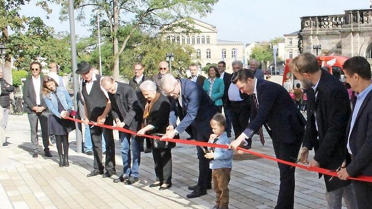 Acht Scheren, achtmal Schnipp-Schnapp - neben Architekten, Vertretern der Stadt, der WSCO und des Landestheaters durften auch ein Kind aus dem Kindergarten Marienhaus und Gertrud Bartelmus (Sechste von rechts), die frühere Betreuerin von Otto Waldrich, das Band durchschneiden und damit den Platz offiziell freigeben. Fotos: Ulrike Nauer