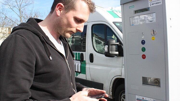Björn Assel tippt sein Kennzeichen und die gewünschte Parkdauer in sein Smartphone.  Foto: Robert Huger