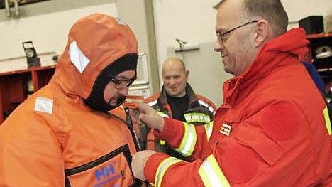 Stephan Murmann (rechts) erläutert den Überlebensanzug, in den Stephan Trapper von der Staffelsteiner Feuerwehr geschlüpft ist.