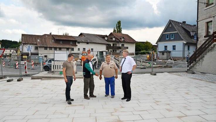 Andreas Schorn (Leiter Bauwesen Markt Pressig), Günther Schubert (SV Rothenkirchen), Jens Fritzsch (Bauleiter), Bürgermeister Hans Pietz (von links) schauen sich den frisch gepflasterten Marktplatz an. Hinten ist der Sockel für das neue Kriegerdenkmal zu sehen sowie die Baustelle der Kreisstraße 9, deren Kurve etwas entschärft wird.  Foto: K.- H. Hofmann