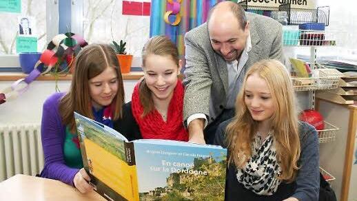 Anna Hünnerkopf, Franziska Schwab (beide Thüngfeld) und Lara Seeger aus Aschbach (von links) betrachten gemeinsam mit ihrem Lehrer Johannes Krapp einen Bildband aus der Region um Larche. Foto: Seeger