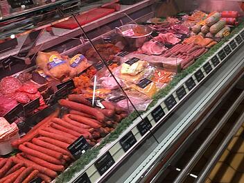Eine Fleischtheke voller verschiedener Wurst- und Fleischsorten in einer Metzgerei.