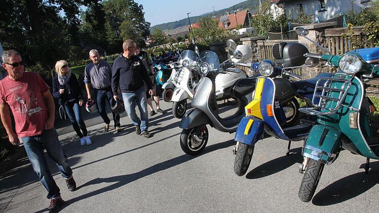 Das Chrom der Vespas glänzt mit der Spätsommersonne um die Wette. Groß und Klein flanieren in Maineck an den alten und neuen Rollern vorbei, die sich wie Perlen an einer Schnur am Bergweg aneinanderreihen. Foto: Stephan Stöckel.