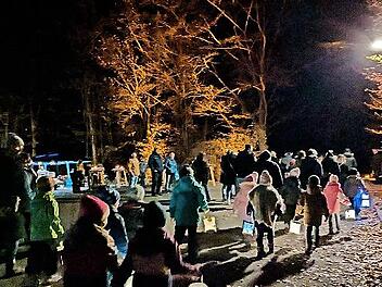Kinder und Eltern ziehen mit ihren Laternen durch den Wald.