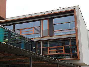 Dort, wo an der Fassade der Höchstadter Realschule heute Latten und eine Plane angebracht sind (linkes Bild), riss 2013 ein Sturm mehrere Bleche ab. Diese sollen eigentlich die Holzkonstruktion  der Regalfassade vor Regen schützen (rechts oben). Allerdings stellte man fest, dass die Schraubenlöcher offen gelegen waren, Wasser eingedrungen war und das Holz zu modern begonnen hatte.Christian Bauriedel