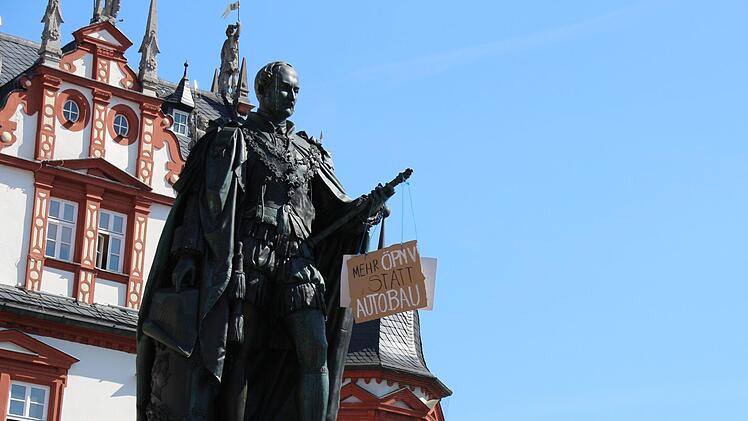 Am Prinz-Albert-Denkmal auf dem Coburger Marktplatz baumelt ein Pappschild - Aufschrift: "Mehr ÖPNV statt Autobau".Christoph Wiedemann