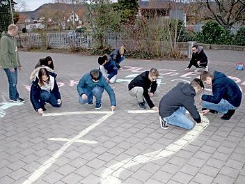 Auch auf dem Pausenhof der Sander Grundschule waren die "Straßenmal-Künstler" der Jugendfeuerwehr aktiv. Dabei schaut der Leiter Frank Winkler (links) zu. In 72 Tagen startet die "72-Stunden-Aktion" des Bundes der Deutschen Katholischen Jugend (BDKJ) und die jungen Sander machen mit.  Foto: Ralf Naumann