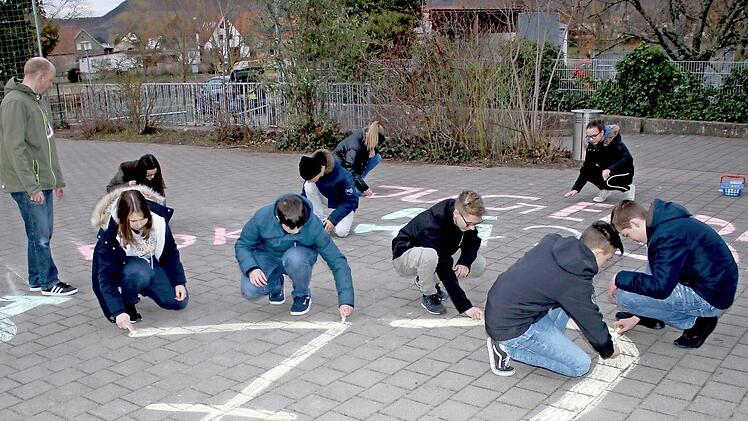 Auch auf dem Pausenhof der Sander Grundschule waren die "Straßenmal-Künstler" der Jugendfeuerwehr aktiv. Dabei schaut der Leiter Frank Winkler (links) zu. In 72 Tagen startet die "72-Stunden-Aktion" des Bundes der Deutschen Katholischen Jugend (BDKJ) und die jungen Sander machen mit.  Foto: Ralf Naumann