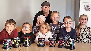 Das Foto zeigt die Kinder mit ihrer selbst gebastelten Halloween- Deko aus leeren Joghurteimern zusammen mit Jungscharleiter Frank Preußners.
