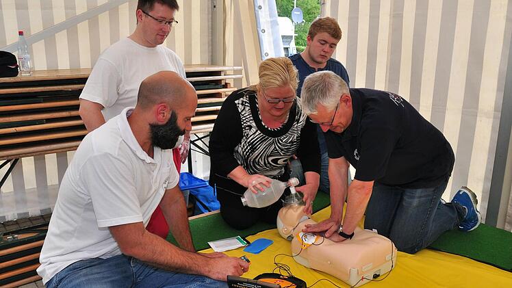 Rainer Klarmann vom BRK (links) erklärte Gudrun Greger, ihrem Sohn Finn (dahinter) und Joachim Dittmer (rechts), wie ein Defibrillator funktioniert. Mit im Bild Mathias Feustel von der Wasserwacht. Foto: Ulrike Langer