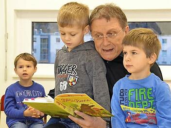 Der fünfjährige Jonas (vorne links) und der vierjährige Jakob (rechts) genießen den Sonderplatz bei der Vorleserunde auf dem Schoß von Oberbürgermeister Henry Schramm. Foto: Uschi Prawitz