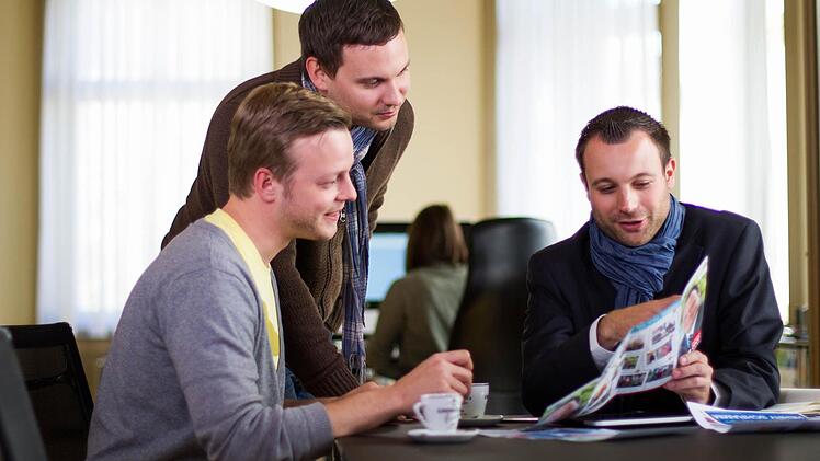 Die Designer Florian Hartl und Daniel Kestler von der Bamberger Werbeagentur medienreaktor nehmen mit Geschäftsführer Jonas Lindner (von links)  die Wahlkampfbroschüren der  OB-Kandidaten unter die Lupe.