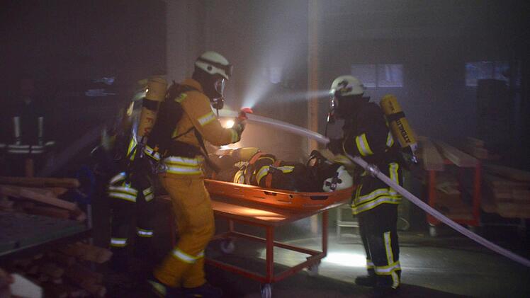 Hier retten die Atemschutzgeräteträger einen verletzten Feuerwehrmann. Sein Team war bei der Suche nach Vermissten vom Feuer eingeschlossen worden. Dank eines Rollwagens konnte er schnell aus der Werkstatt transportiert werden. Foto: Kathrin Kupka-Hahn