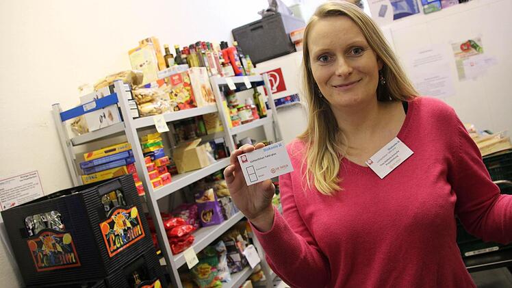 Stefanie Kreische steht in dem kleinen Raum in der Striwa, in der die Tafel ihre Lebensmittel aufbewahrt und zeigt den Ausweis, der zum Einkauf dort berechtigt. Fotos: Tobias Kindermann