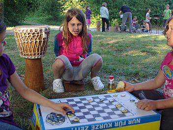 Damespiel selbst gemacht: Meike, Svenja und Annika vergnügen sich am Gemüsekarton, auf dem  mit Kronkorken gespielt wird. Fotos: Elisabeth Assmann