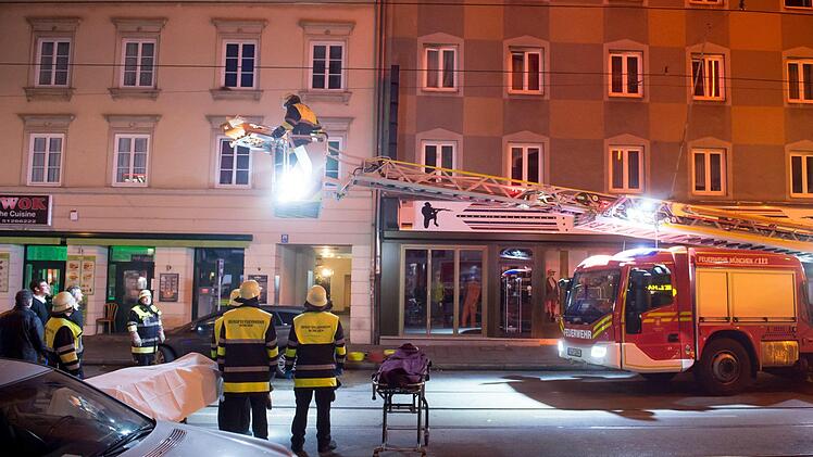 Ein Feuerwehrmann transportiert an einem Einsatzort eine Leiche mit einer Trage am Korb einer Drehleiter. Bei einem Brand an der Dachauer Stra&szlig;e sind drei Menschen ums Leben gekommen, zehn weitere wurden verletzt. Foto: Tobias Hase/dpa