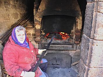 Die "Scharrn" oder "Krücke" in der Hand, wacht Elisabeth Roth über die richtige Temperatur in ihrem Holzbackofen. Foto: Helmut Will