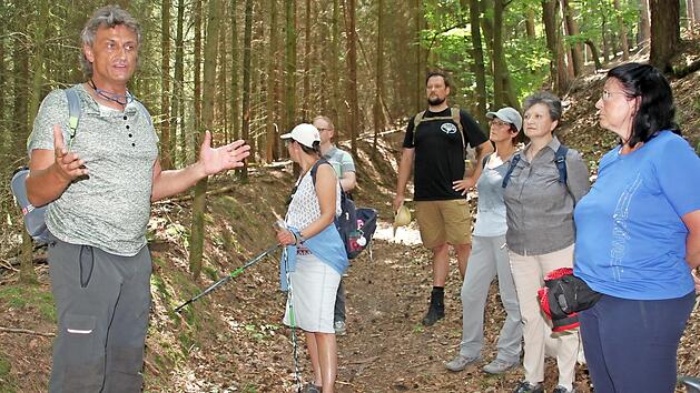 16 Frauen und M&auml;nner nehmen am Waldbaden teil. Waldp&auml;dagoge Stefan Hanke erz&auml;hlt ihnen Wissenswertes &uuml;ber den Wald.