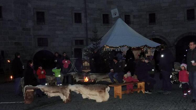 Am Lagerfeuer wärmen sich die  Besucher vor stimmiger Kulisse.