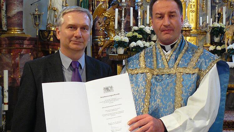 Der Vorsitzende des Förderverein "Freunde der Wallfahrtsbasilika Marienweiher", Monsignore Professor Rüdiger Feulner (rechts), nahm am Altar die Stiftungsurkunde von Leitendem Regierungsdirektor Armin Helbig entgegen. Foto: Klaus-Peter Wulf
