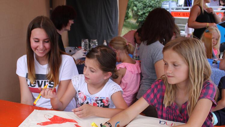 Herzen und  kunterbunte Muster malten die Kinder auf ihre Turnbeutel. Hannah Hendel betreute die Station und half Lea Hollweg (8) und Ida Sünkel (10). Foto: Sonny Adam
