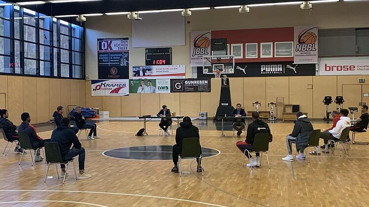 An Tischen sitzend haben Geschäftsführer Arne Dirks (links) und der Aufsichtsratsvorsitzenden Michael Stoschek (rechts) die Trainer und noch unter Vertrag stehenden Spieler der Bundesliga-Mannschaft im Trainingszentrum in Strullendorf um sich versammelt.  Foto: Brose Bamberg