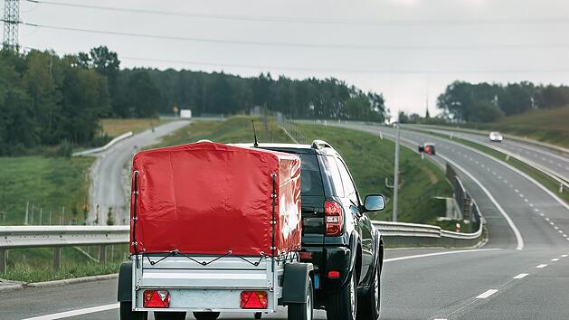 SUV und Mietladungsanh&auml;nger auf einer Stra&szlig;e. Effizienter Umzug.