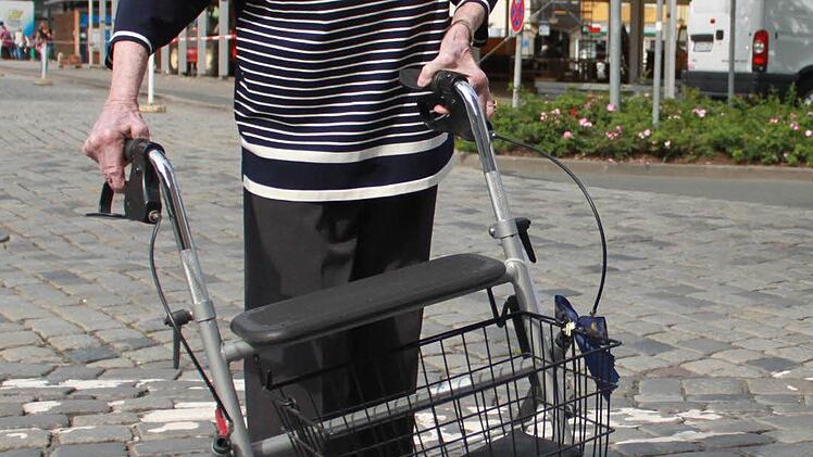 Auf dem Kopfsteinpflaster stellen sich am Bordstein die Lenkräder quer: Nichts geht mehr, der Gehwagen muss angehoben werden.