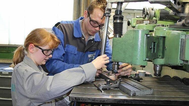 Michelle Martin bearbeitet mit Unterstützung von Manuel Fröba bei der Gerresheimer Tettau GmbH ihren herzförmigen Schlüsselanhänger, auf den sie ihren Namen fräst.