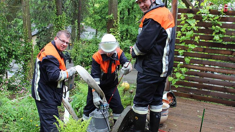 Etzelskirchener Feuerwehrleute lassen eine Pumpe in einen Revisionsschacht und legten einen überfluteten Keller trocken. Foto: Andreas Dorsch