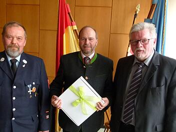 Der Feuerwehrkommandant Bernd Lemser (links) und Zweiter Bürgermeister Joachim Hassel (rechts) danken Bernd Reisenweber für 40 Jahre Feuerwehrdienst. Foto: Lothar Weidner