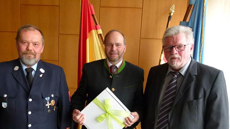 Der Feuerwehrkommandant Bernd Lemser (links) und Zweiter Bürgermeister Joachim Hassel (rechts) danken Bernd Reisenweber für 40 Jahre Feuerwehrdienst. Foto: Lothar Weidner