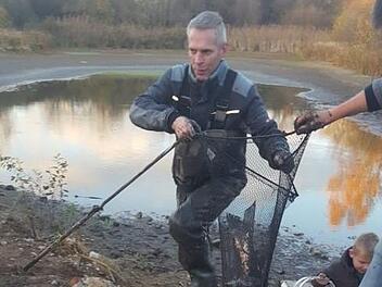Gunar Rusche setzte die Fische in den gegen&uuml;berliegenden Weiher um, mit Unterst&uuml;tzung aus der Nachbarschaft. Bei der Rettungsaktion versank er teils bis zum Bauchnabel im Schlamm.  Fotos: Silke Schmittlutz (oben), Klug (Stadt Bamberg/Umweltamt)
