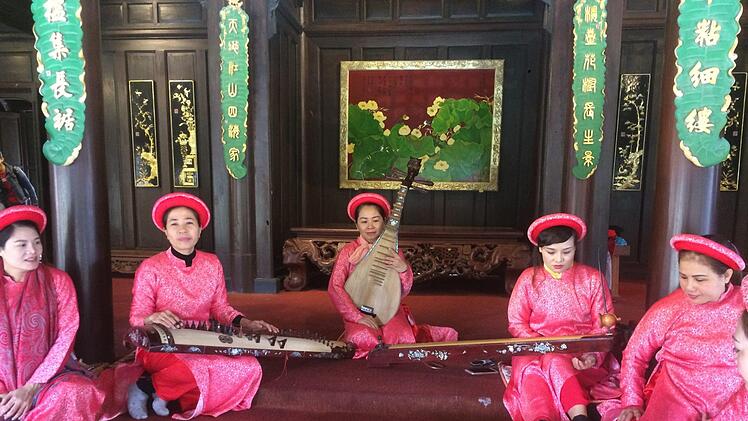 Vor einem Kloster in Vietnam musizieren diese Damen in traditioneller Tracht.privat