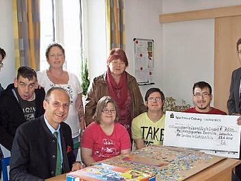 Die HPZ-Gesamtleiterin Maria Wiehle (stehend 2. v. re.), eine Mitarbeiterin und mehrere Bewohner freuten sich über die großzügige Spende der Sparkasse in Höhe von 7500 Euro, die der Vorstandsvorsitzende Siegfried Wölki (re.) und der Vorsitzende des Verwaltungsrats, Landrat Christian Meißner (sitzend li.), überreichten. Foto: Alfred Thieret