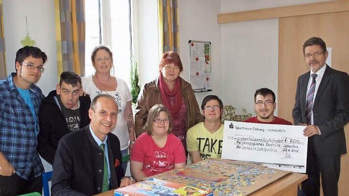 Die HPZ-Gesamtleiterin Maria Wiehle (stehend 2. v. re.), eine Mitarbeiterin und mehrere Bewohner freuten sich über die großzügige Spende der Sparkasse in Höhe von 7500 Euro, die der Vorstandsvorsitzende Siegfried Wölki (re.) und der Vorsitzende des Verwaltungsrats, Landrat Christian Meißner (sitzend li.), überreichten. Foto: Alfred Thieret