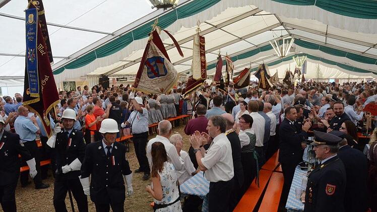 Zum Einmarsch der Fahnenabordnungen haben sich Ehrengäste und Kreisbrandinspektion von den Plätzen erhoben. Foto: Karl-Heinz Hofmann