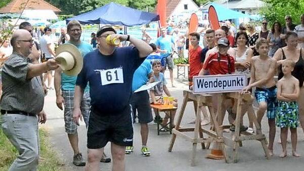 Echte Sportfreunde. Pfarrer Christoph Teille g&ouml;nnt sich beim Wendepunkt der 3800 Meter Laufstrecke einen Becher Wasser w&auml;hrend B&uuml;rgermeister Egon Herrmann als begeisterter Zuschauer mit dem Hut etwas Wind spendet (links). - Die Wasserwettbewerbe machten, im 25 Grad warmen Wasser, an diesem hei&szlig;en Tag als Abk&uuml;hlung gef&uuml;hlt, bei diesen Au&szlig;entemperaturen besonders gro&szlig;e Freude. Den j&uuml;ngsten Teilnehmern wurde aus dem Schwimmbecken geholfen, dann ging es zum 500 Meter Lauf. Fotos: Karl-Heinz Hofmann