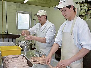Metzgermeister und Juniorchef Markus Alles bereitet den Darm für die Bratwurstfüllung vor, während Lehrling Christopher Albert die Würste abbindet und somit portioniert. Foto: Kathrin Kupka-Hahn