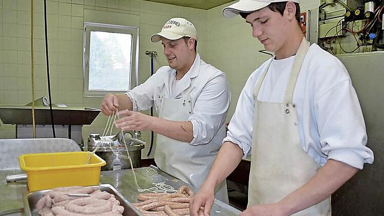 Metzgermeister und Juniorchef Markus Alles bereitet den Darm für die Bratwurstfüllung vor, während Lehrling Christopher Albert die Würste abbindet und somit portioniert. Foto: Kathrin Kupka-Hahn