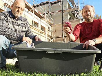 Wolfgang Bayer (links) und Gerhard Kornmann leeren eine Bauwanne mit Wasser aus dem Schützenheim aus.  Fotos: Benedikt Borst
