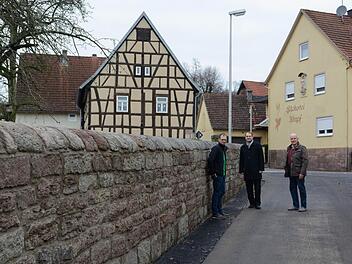 Sind froh darüber, dass die Mauer am Aschacher Kindergarten nicht abgerissen wurde (von links): Andreas Brehm (Rechnungsführer der Kirchenstiftung), Pfarrer Michael Kubatko und Kirchenpfleger Walter Hein. Foto: Björn Hein