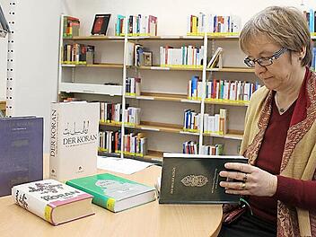Brigitte Maisch mit den nunmehr fünf Koran-Ausgaben, die in der Coburger Stadtbücherei ausgeliehen werden können. Im Neuzugang in ihrer Hand stehen Deutsch und Hocharabisch nebeneinander, ergänzt durch ausführliche Erläuterungen. Foto: Ulrike Nauer