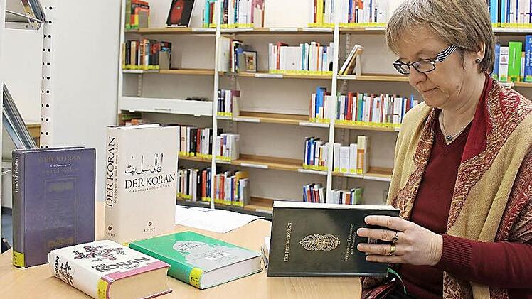 Brigitte Maisch mit den nunmehr fünf Koran-Ausgaben, die in der Coburger Stadtbücherei ausgeliehen werden können. Im Neuzugang in ihrer Hand stehen Deutsch und Hocharabisch nebeneinander, ergänzt durch ausführliche Erläuterungen. Foto: Ulrike Nauer